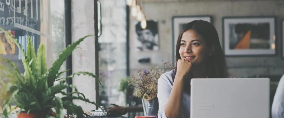Vrouw aan het werk op haar laptop in een café en kijkt uit het raam  - Nestlé Professional