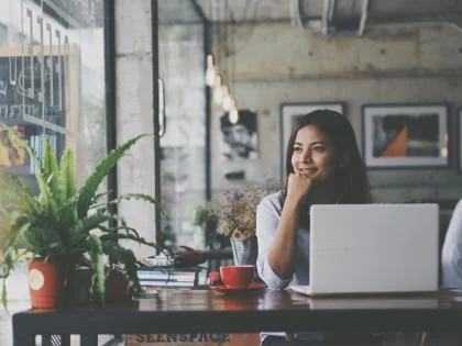 Vrouw aan het werk op haar laptop in een café en kijkt uit het raam  - Nestlé Professional