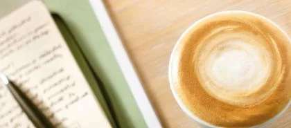 Kop schuimende koffie naast een notitieboekje - Nestlé Professional