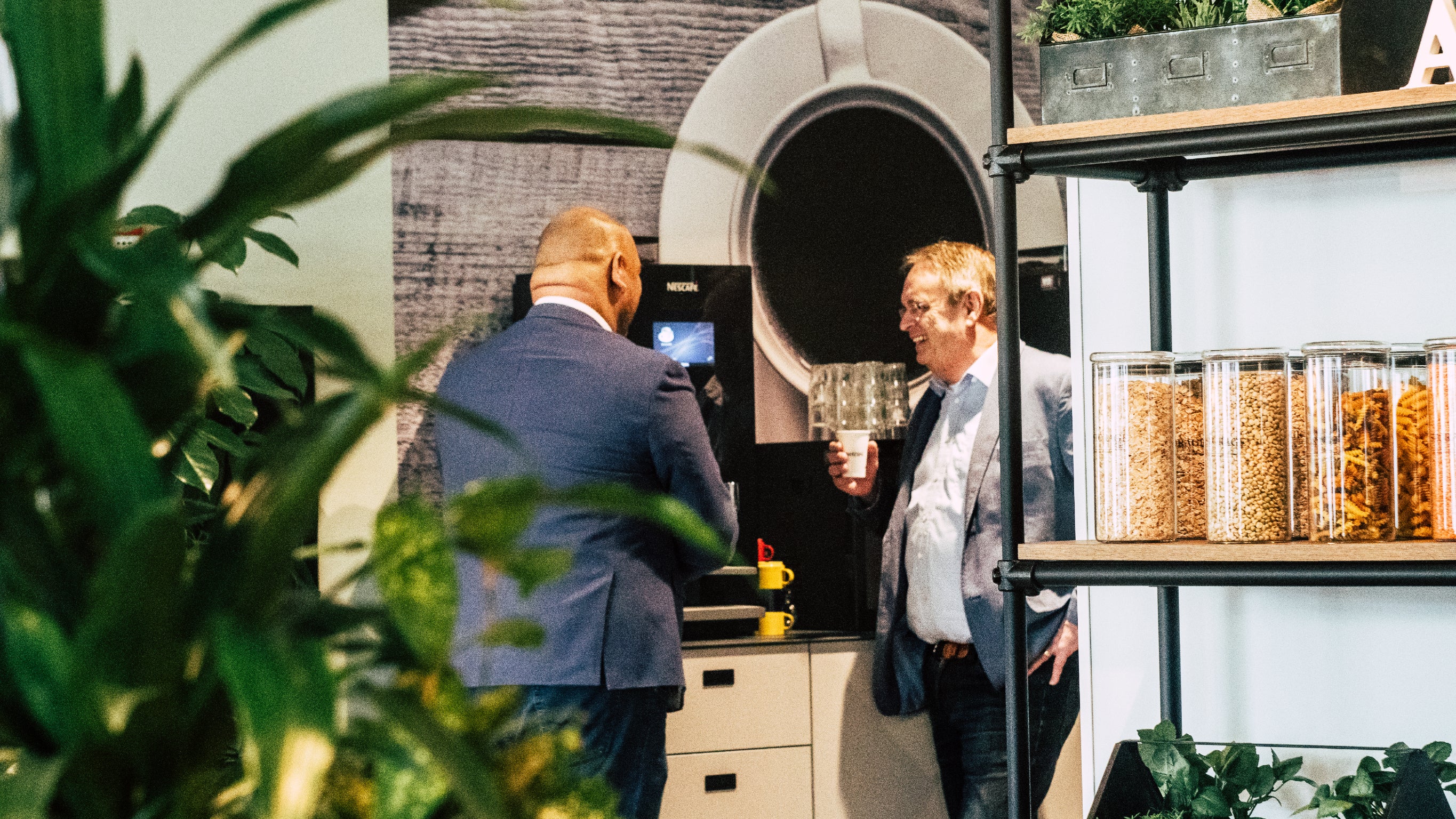 Twee mannen in pak drinken koffie bij een Nescafé koffiezetapparaat - Nestlé Professional