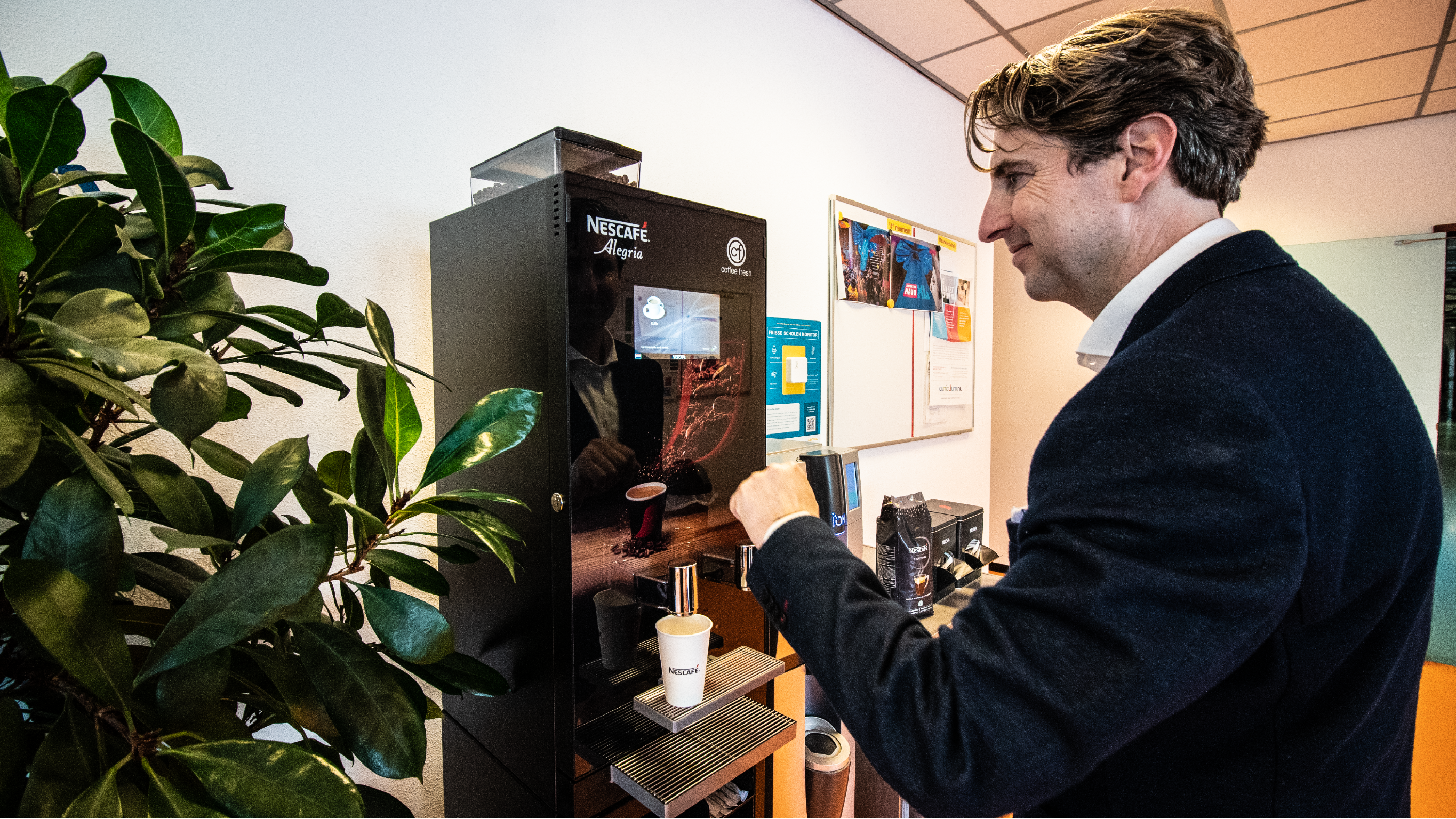 Man pakt een kopje Nescafé koffie uit het koffiezetapparaat in de kantine - Nestlé Professional