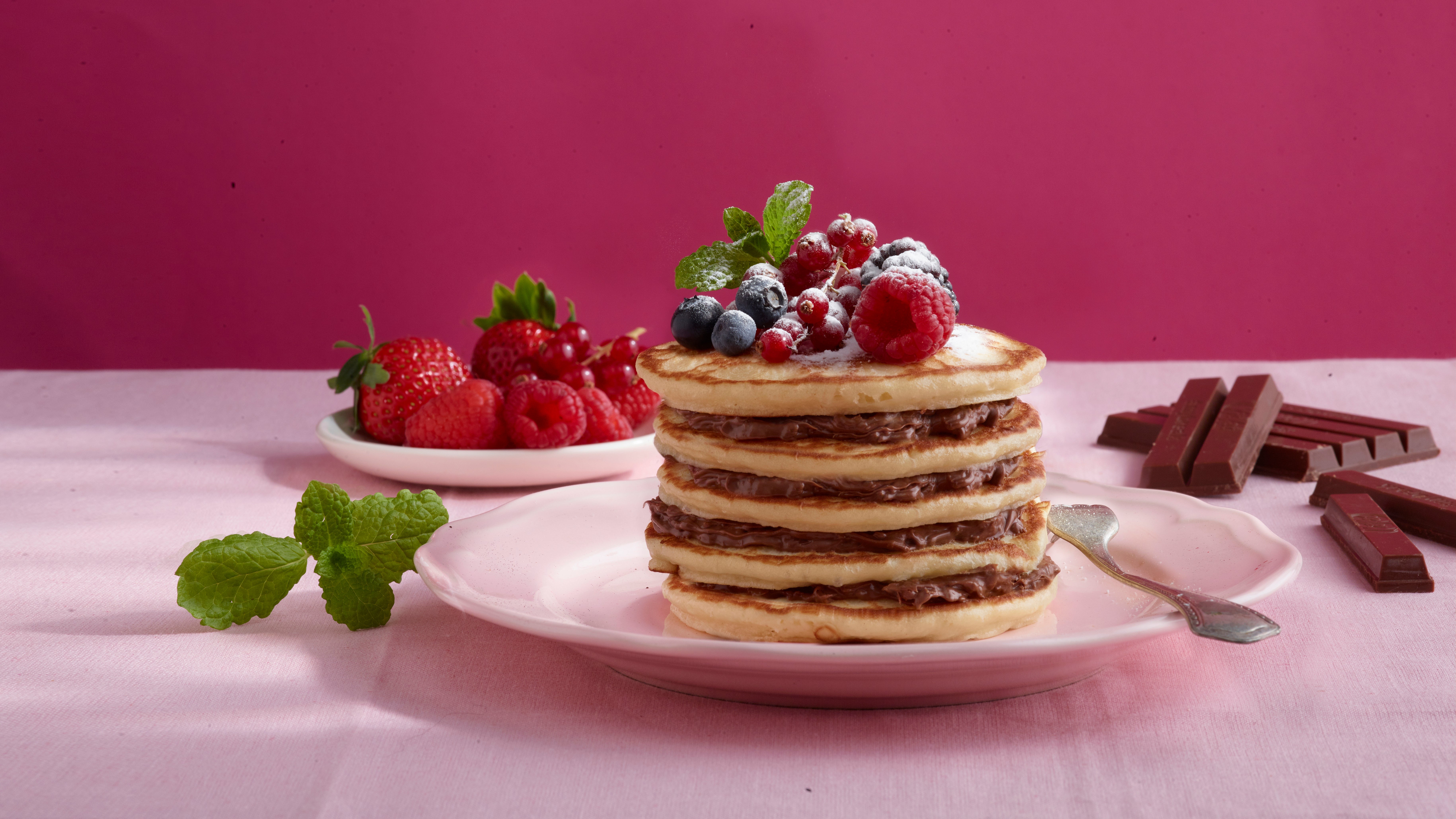 Stapel pannenkoeken met rood fruit en kitkat voor een roze achtergrond - Nestlé Professional