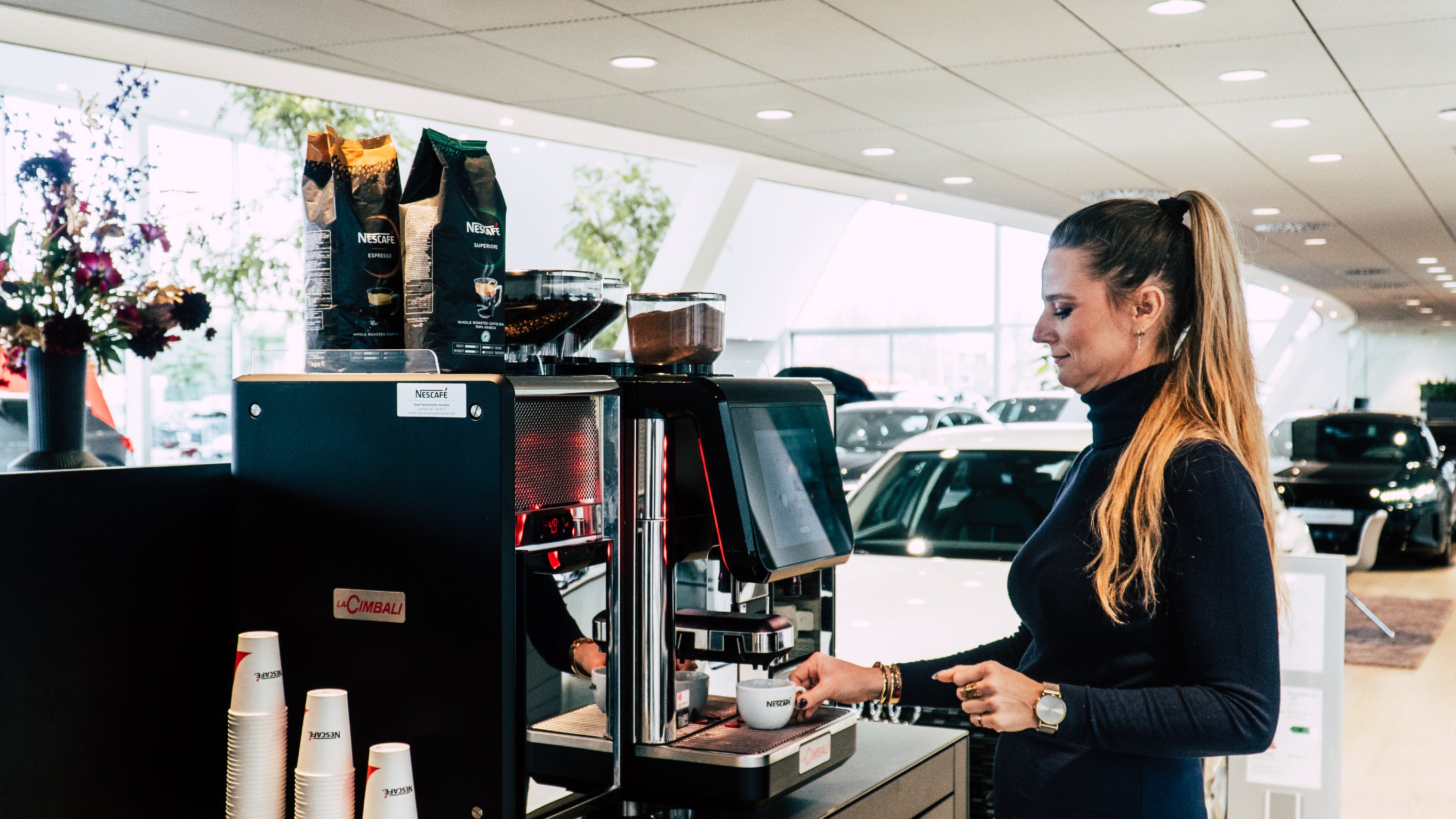 Dame in autozaak zet een kopje Nescafé koffie - Nestlé Professional