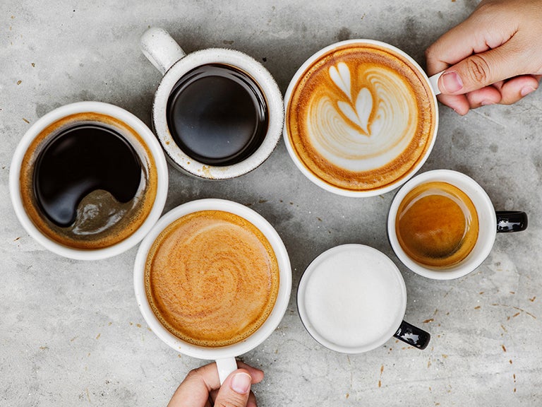 Bovenaanzicht van koppen zwarte koffie en koppen koffie met melkkunst - Nestlé Professional