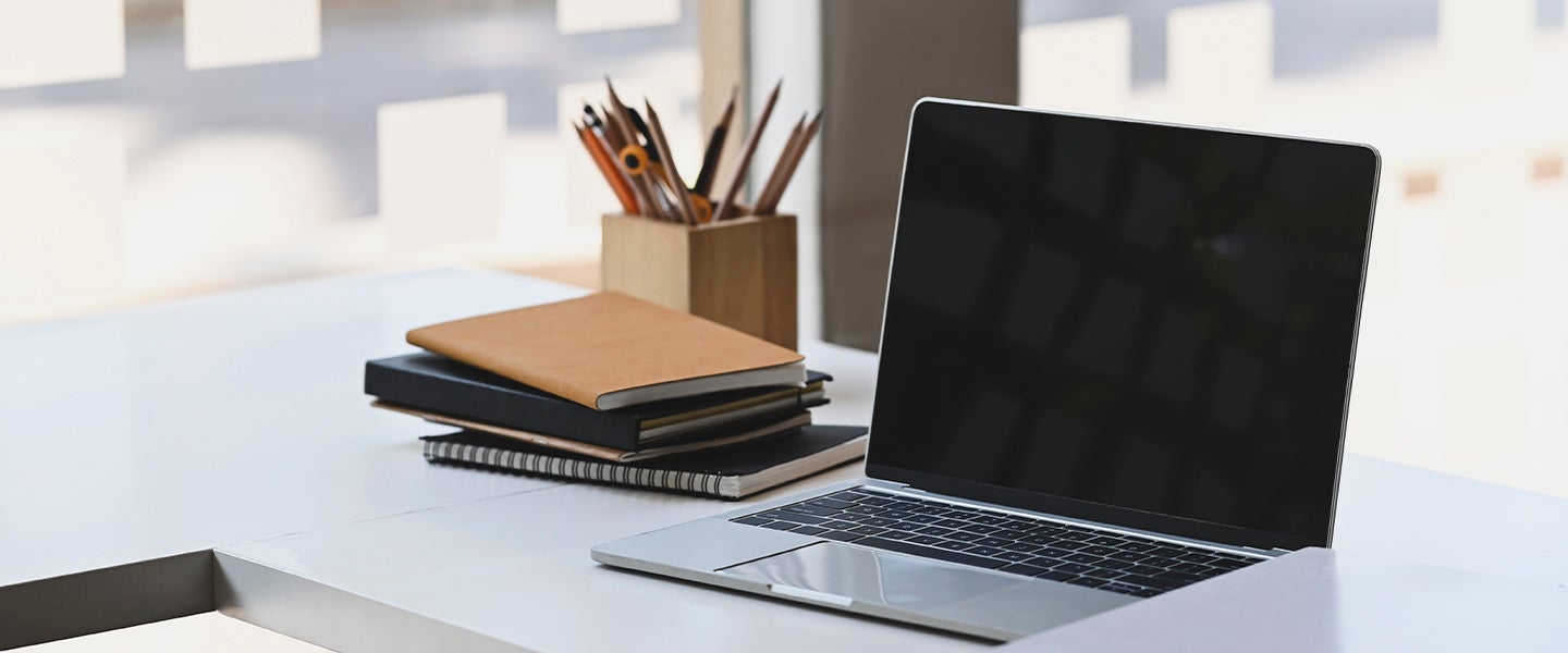 Laptop op bureau met notitieblokken ernaast - Nestlé Professional