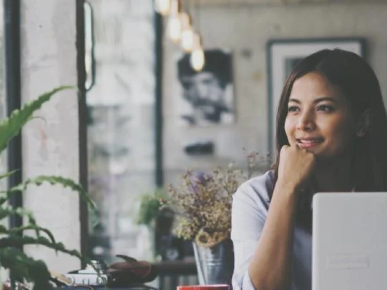 Vrouw aan het werk op haar laptop in een café en kijkt uit het raam  - Nestlé Professional