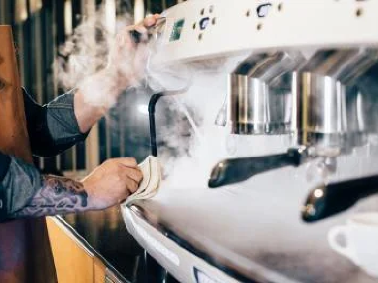 Barista maakt een rokende koffiemachine schoon - Nestlé Professional