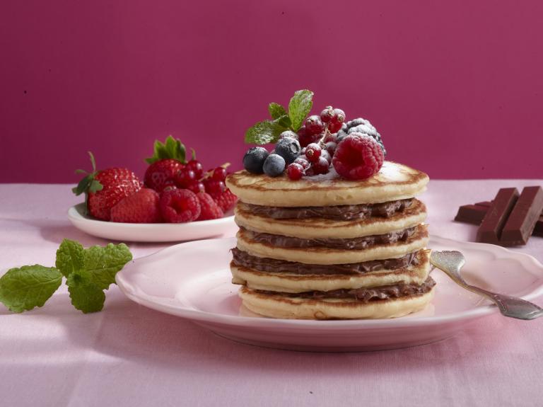 Stapel pannenkoeken met rood fruit en kitkat voor een roze achtergrond - Nestlé Professional