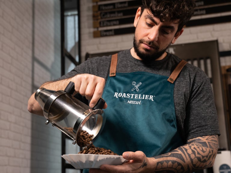 Koffiemedewerker schenkt ROASTELIER gemalen koffie in