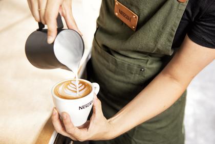 Barista tekent met melk een figuur in een kopje Nescafé koffie - Nestlé Professional