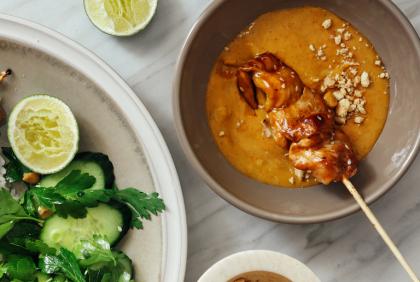 Bovenaanzicht van saté met satésaus en een bord met salade - Nestlé Professional