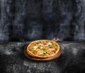 Een pizza op een houten bord op een donkere achtergrond