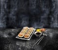 Sushi op een bord met eetstokjes op een donkere achtergrond