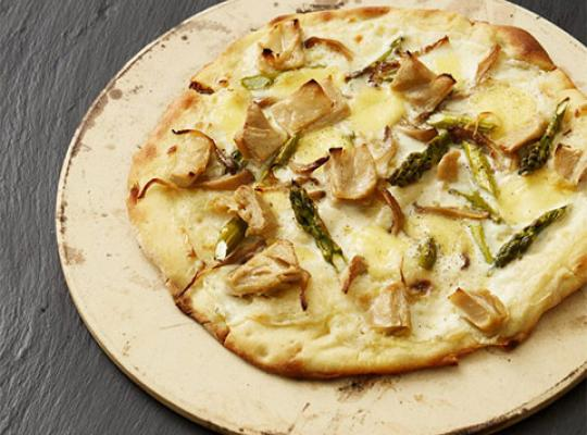 Veganische witte pizza op een bord op een zwarte achtergrond