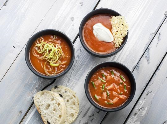 Drie kommen tomatensoep op houten oppervlak