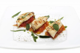 Drie stukjes vis op een wit bord met salie