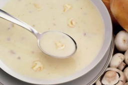 Een kom soep met een lepel met champignons