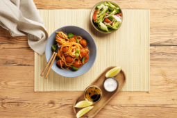 Een kom noedels en salade op een tafel