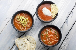Drie kommen tomatensoep op houten oppervlak