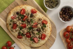 Een pizza met tomaten en olijven op een houten bord