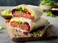 Een burrito met vlees en groenten op een snijplank