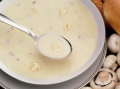 Een kom soep met een lepel met champignons