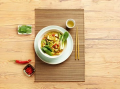 Thaise groene curry in een witte kom op een bruine placemat