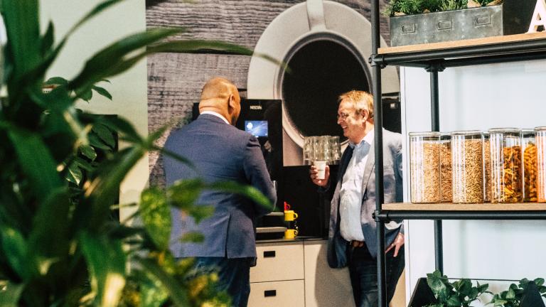 Twee mannen in pak drinken koffie bij een Nescafé koffiezetapparaat - Nestlé Professional
