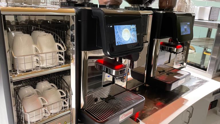 Kopjes in een rek naast twee Nescafé koffiezetapparaten - Nestlé Professional